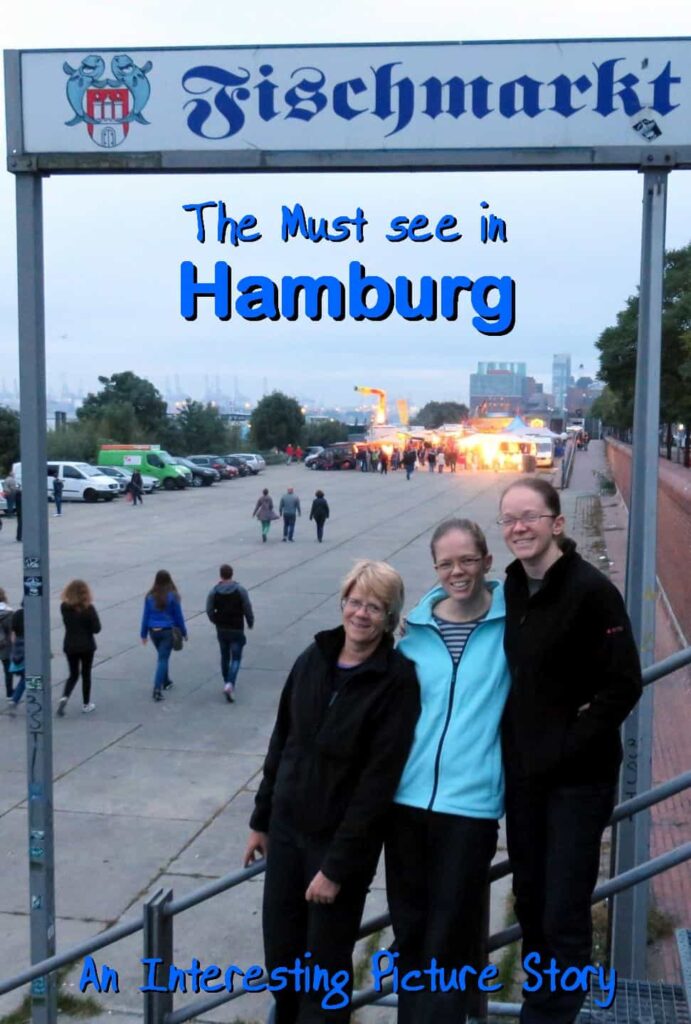 Three smiling people stand under a Fischmarkt sign in Hamburg at dusk. A crowd strolls along the paved area toward a distant building with glowing lights. The sign proclaims: "The Must see in Hamburg." At the bottom, it notes: "An Interesting Picture Story.