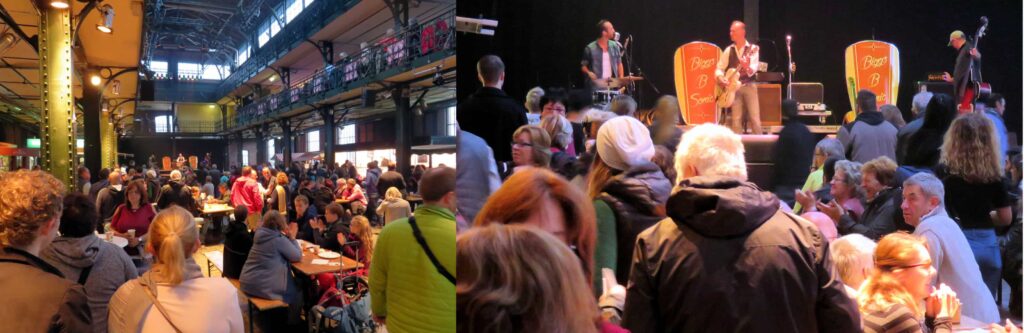 The bustling indoor venue resembles the lively atmosphere of Hamburg's Fischmarkt, with people seated at tables on the left while others gather around a live band performing energetically on stage to the right. The space buzzes with activity and vibrant conversations.
